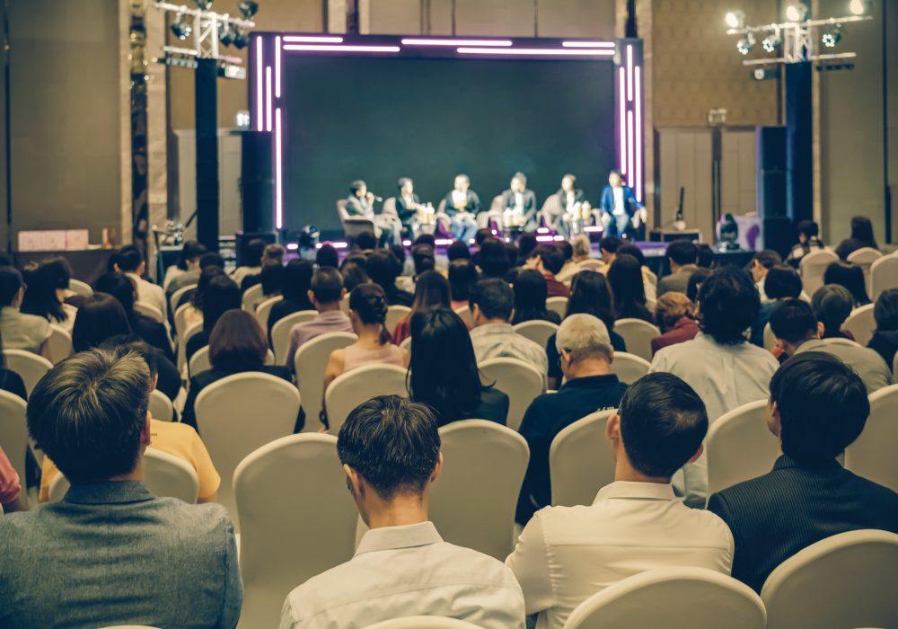 Rear view of Asian audience joining and listening group of speaker talking on the stage in the seminar meeting room or conference hall, business and education, associate and startup business concept